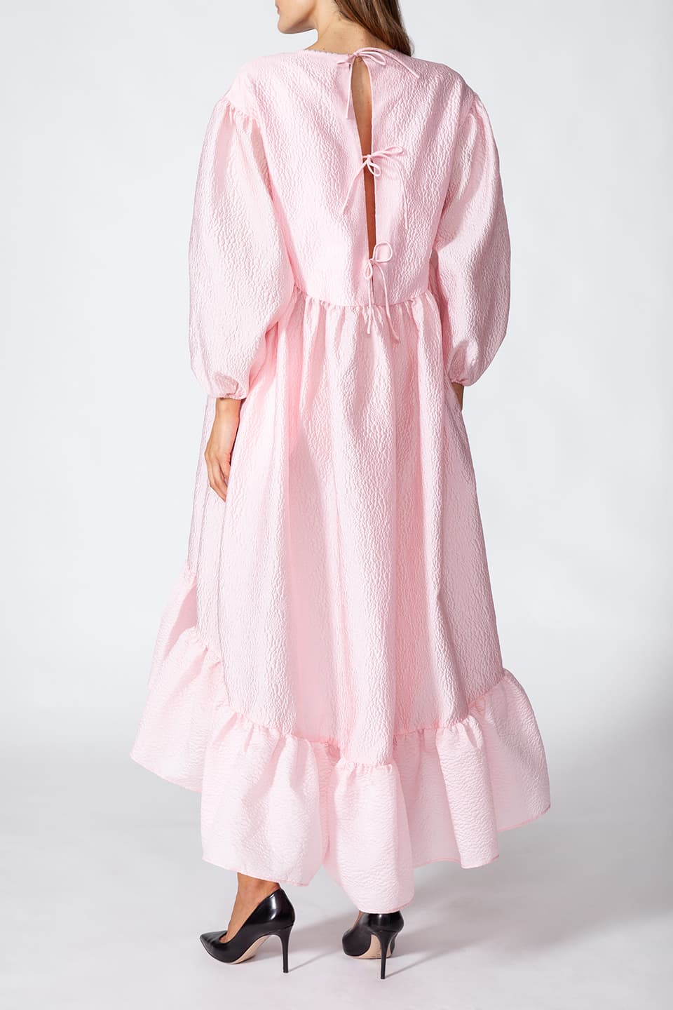 Model in pose from behind wearing Manoush sylist pink long dress with puffy sleeves. Scalloped neck with contrasting stitching.
