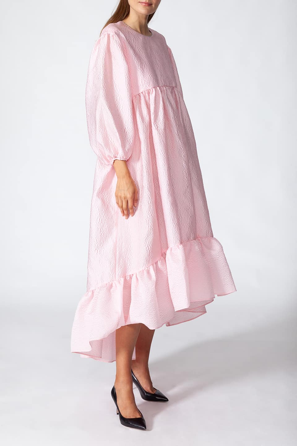 Model in pose for side view wearing Manoush sylist pink long dress with puffy sleeves. Scalloped neck with contrasting stitching.