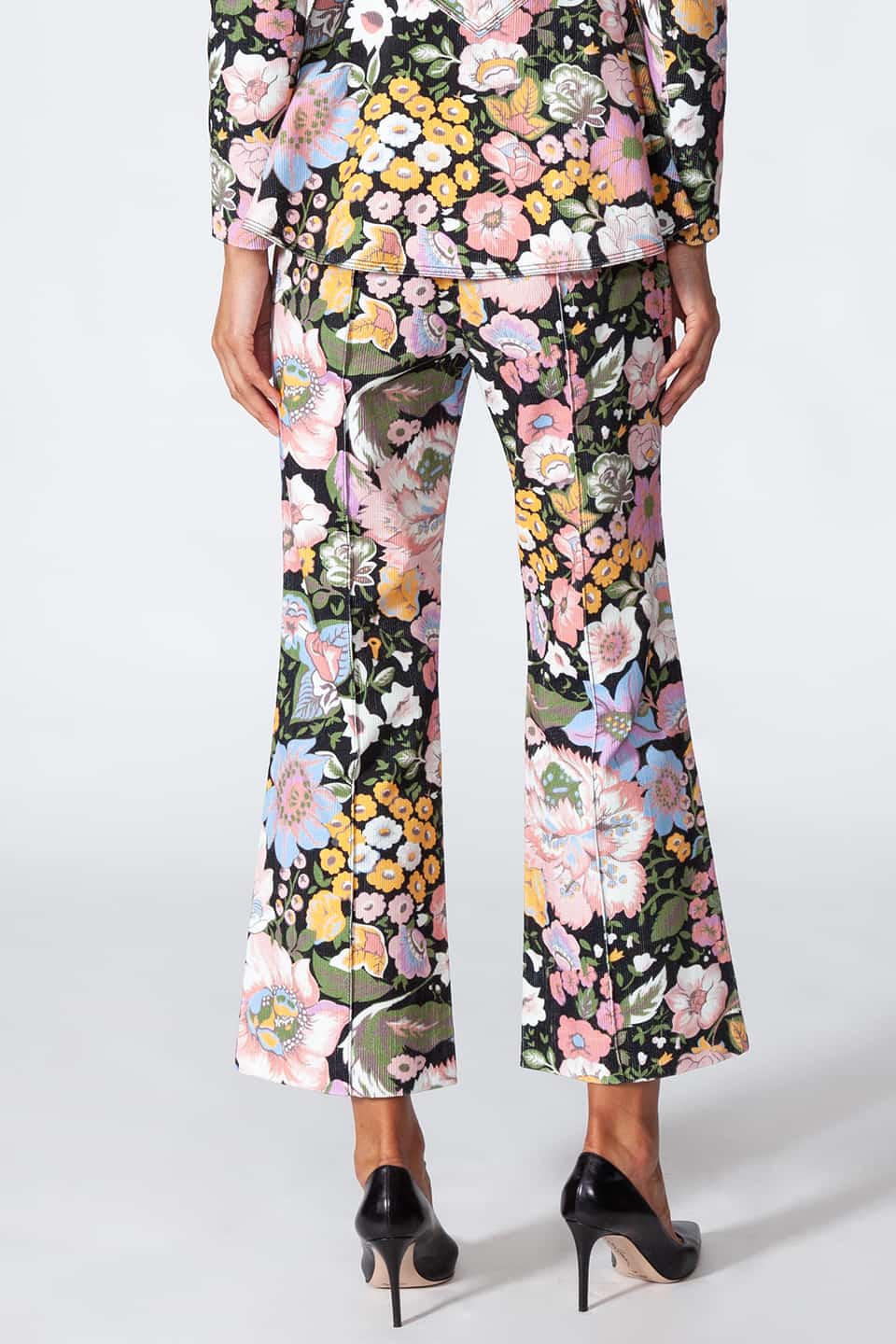 Model showing Manoush European stylist's flare trousers in corduroy with floral print, back view with jacket.