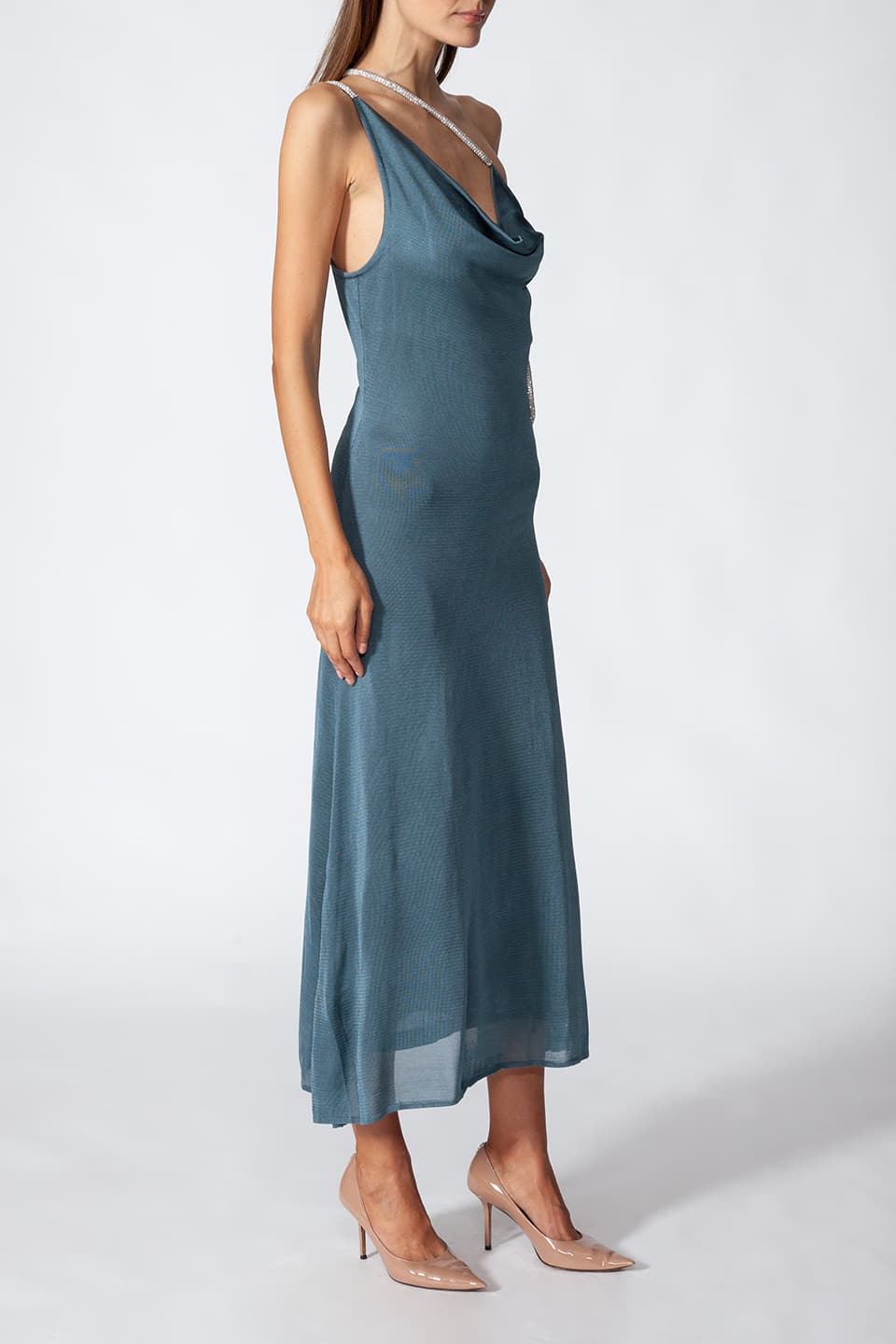 Model in pose from side view, while wearing midi length dress featuring cut out details in petrol blue color, from Kukhareva London fashion stylist