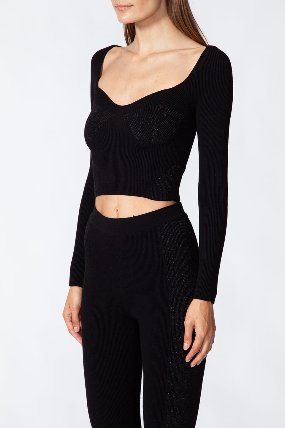 Model posing for side view, wearing stylist Kukhareva London's trendy black top, with cut out neckline and inserts threaded with metallic, shimmering yarn.