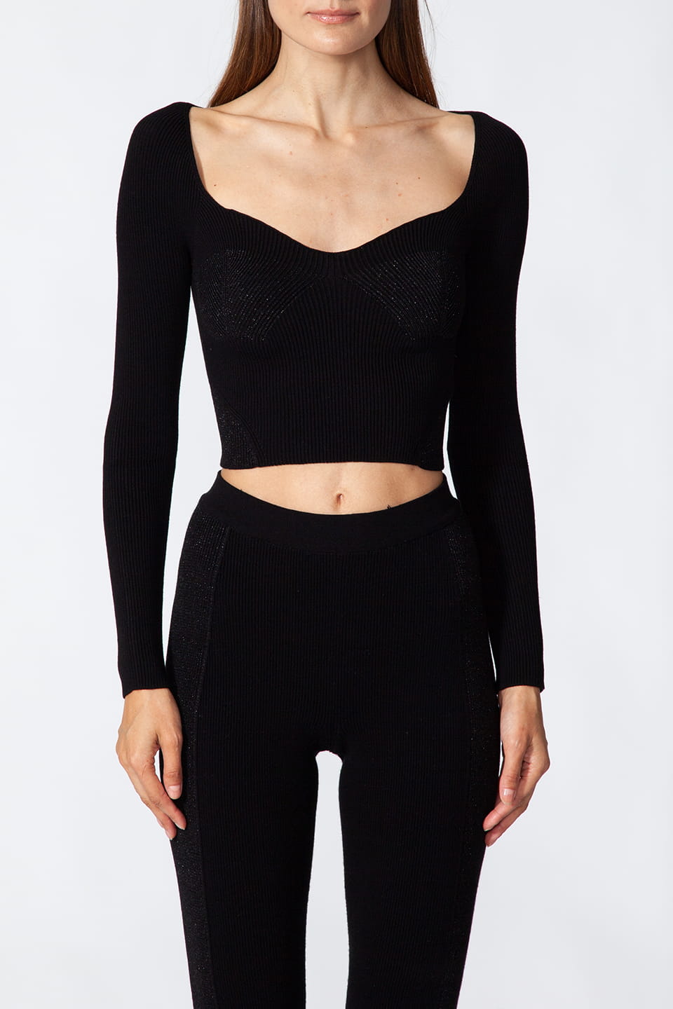 Model posing for front view, wearing stylist Kukhareva London's trendy black top, with cut out neckline and inserts threaded with metallic, shimmering yarn.