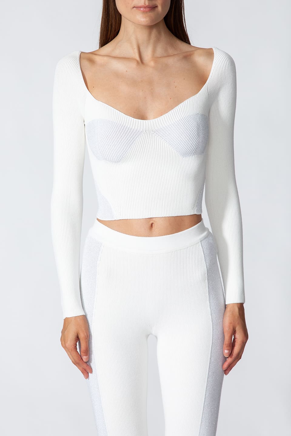 Model in pose while wearing fashion artist Kukhareva London's trendy white top, with cut out neckline and inserts threaded with metallic, shimmering yarn.