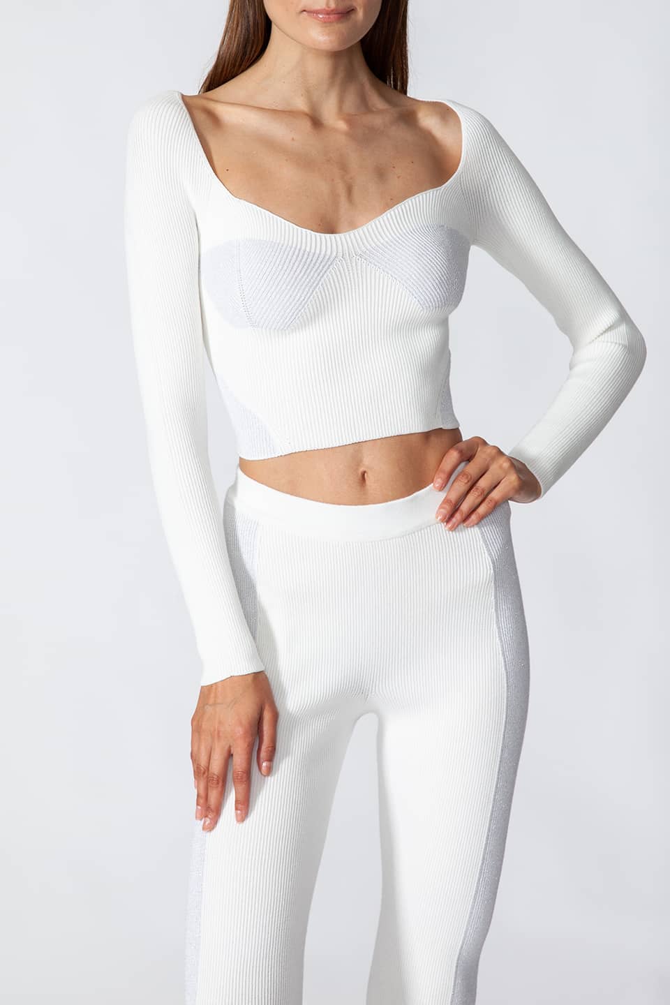 Model in a natural pose while wearing fashion artist Kukhareva London's trendy white top, with cut out neckline and inserts threaded with metallic, shimmering yarn.