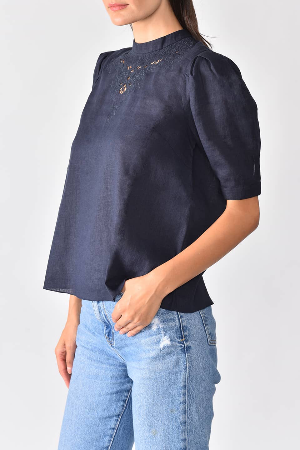Model wears navy linen top with floral cutout embroidery from stylist Vilshenko, posing on left side
